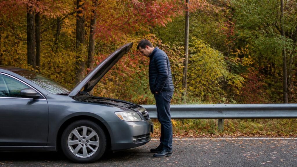 A stalled car on the side of the road in early fall.
