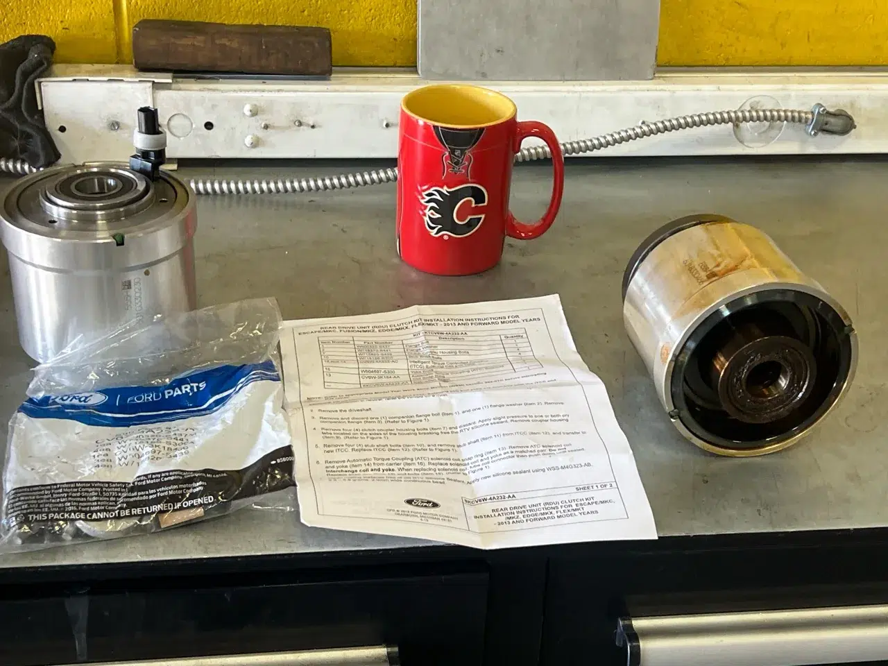 Replacement and old Ford Escape torque couplings side by side on the workbench