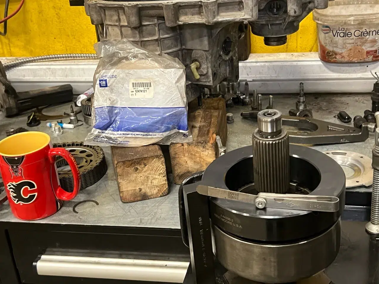 Transfer-case assembly held in tooling with parts packaging on the workbench